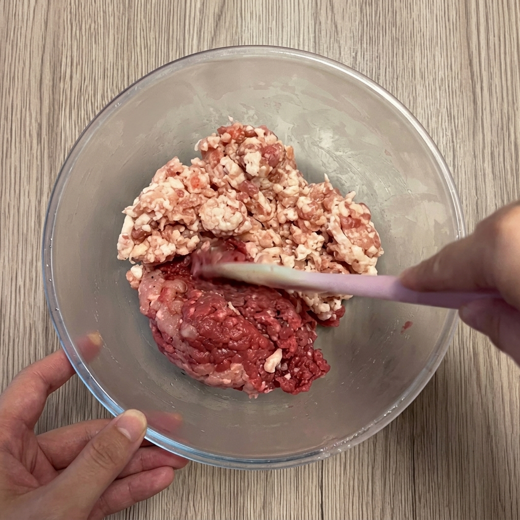 Porc et bœuf hachés dans un saladier en verre.