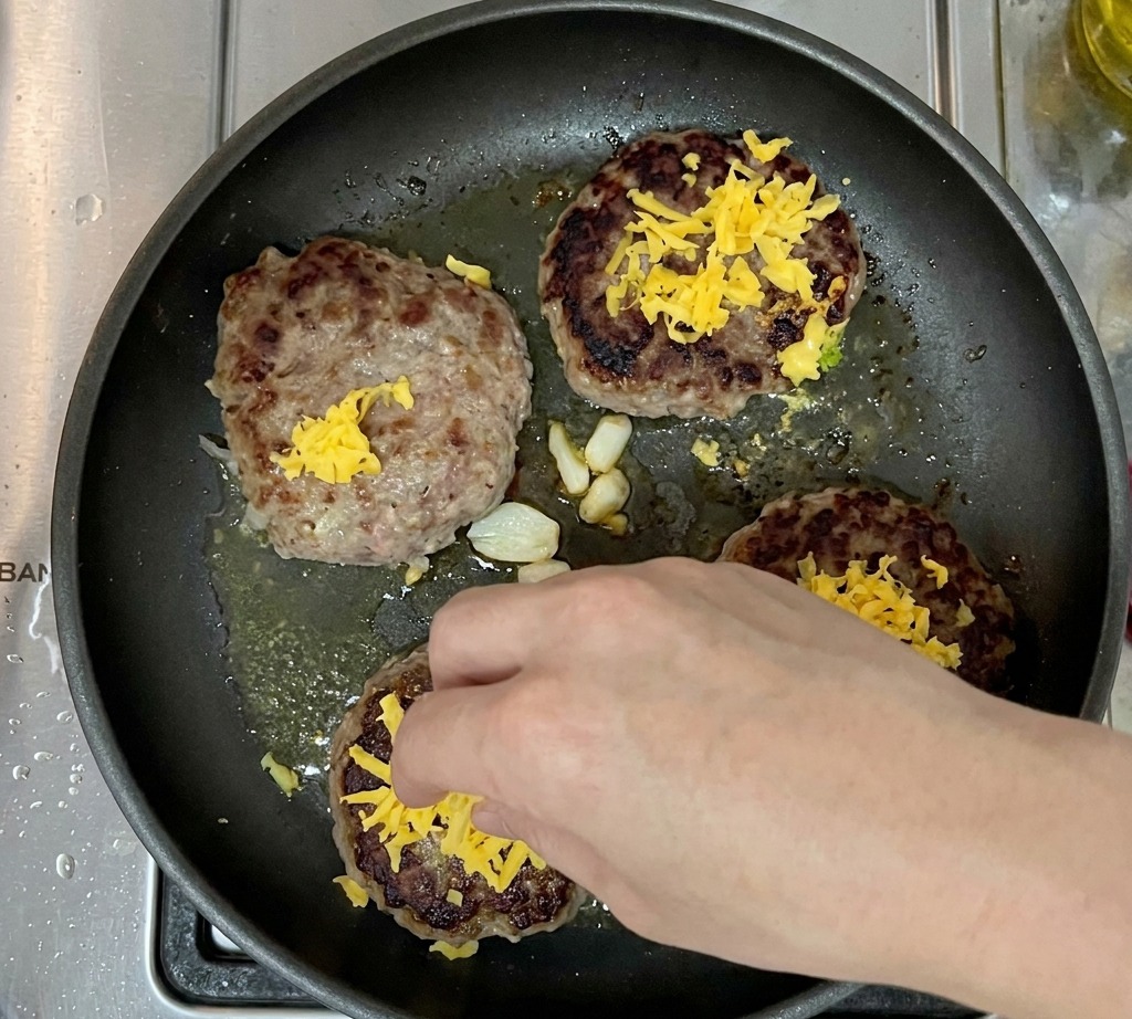 Steaks recouverts de cheddar râpé dans la poêle.