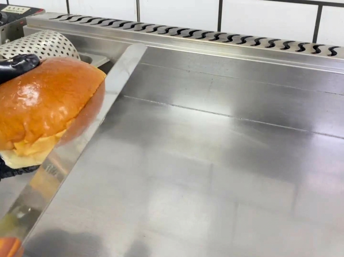 Moitiés de pain à hamburger dorant sur une plaque chauffante.