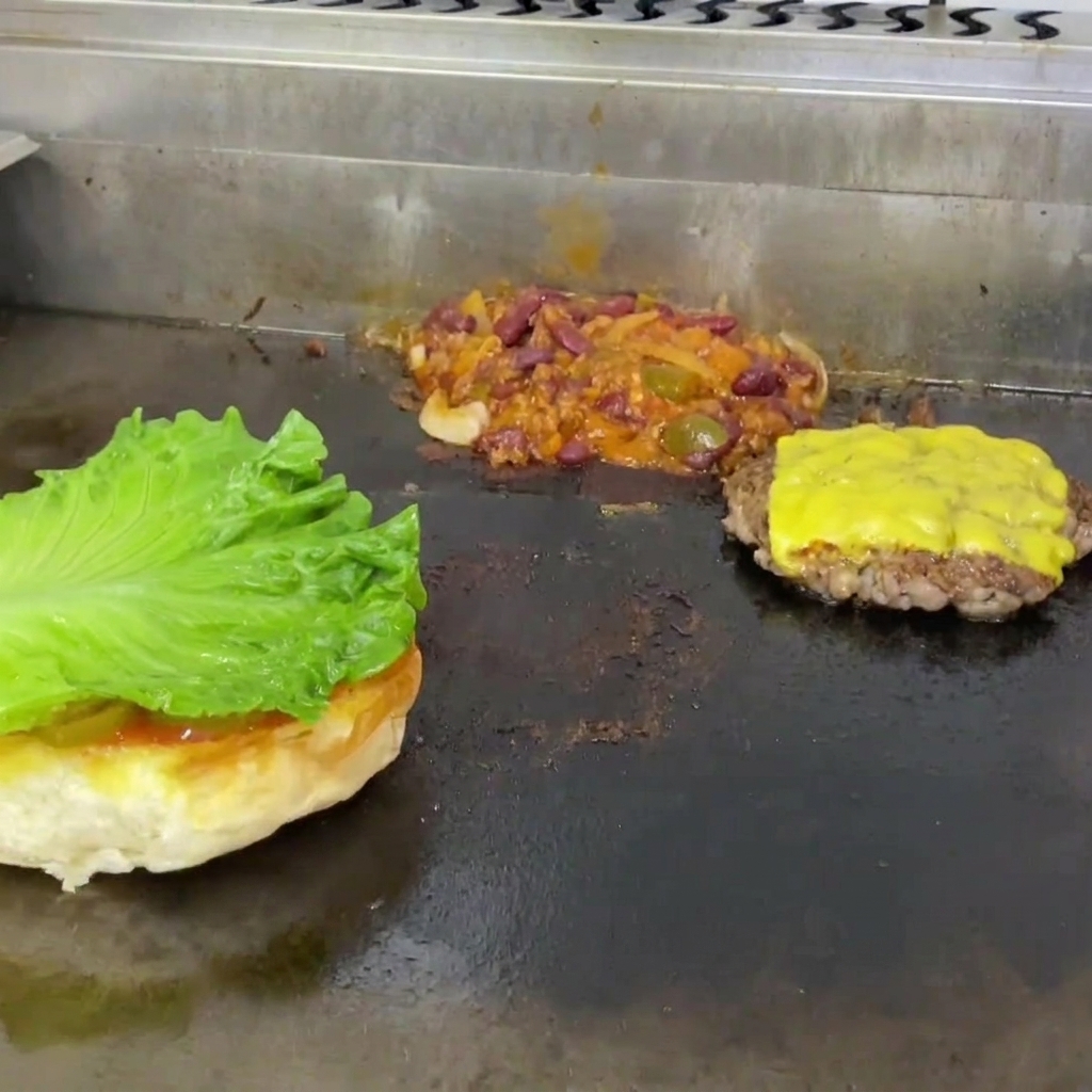 Laitue et tranche de tomate disposées sur un pain à hamburger grillé.