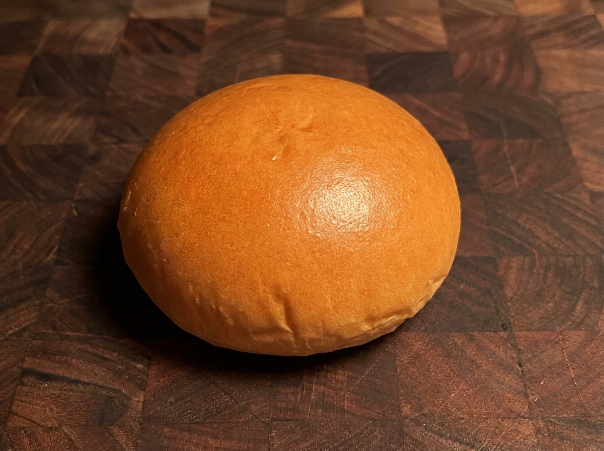 Un pain à burger toasté doré reposant sur une surface en bois.