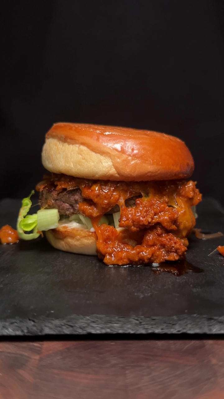 Un burger au Choriqueso gastronomique avec un steak épais et une sauce au chorizo onctueuse sur un pain toasté.
