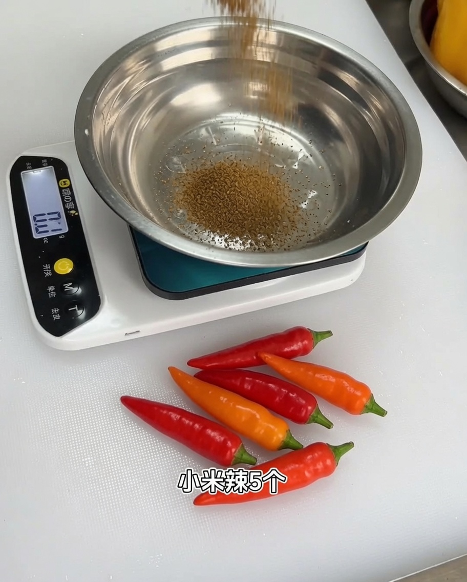 Un mélange dépices en poudre mesuré dans un bol en métal sur une balance de cuisine numérique.