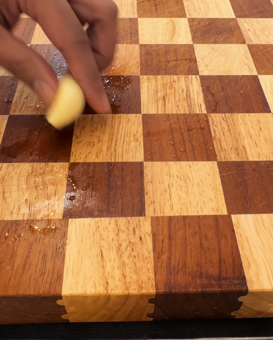 Gousses dail finement émincées sur une planche à découper en bois avec un grand couteau.