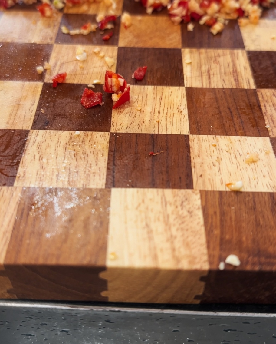 Un mélange dail émincé et de piments hachés combiné avec de lhuile dolive dans un bol en inox.