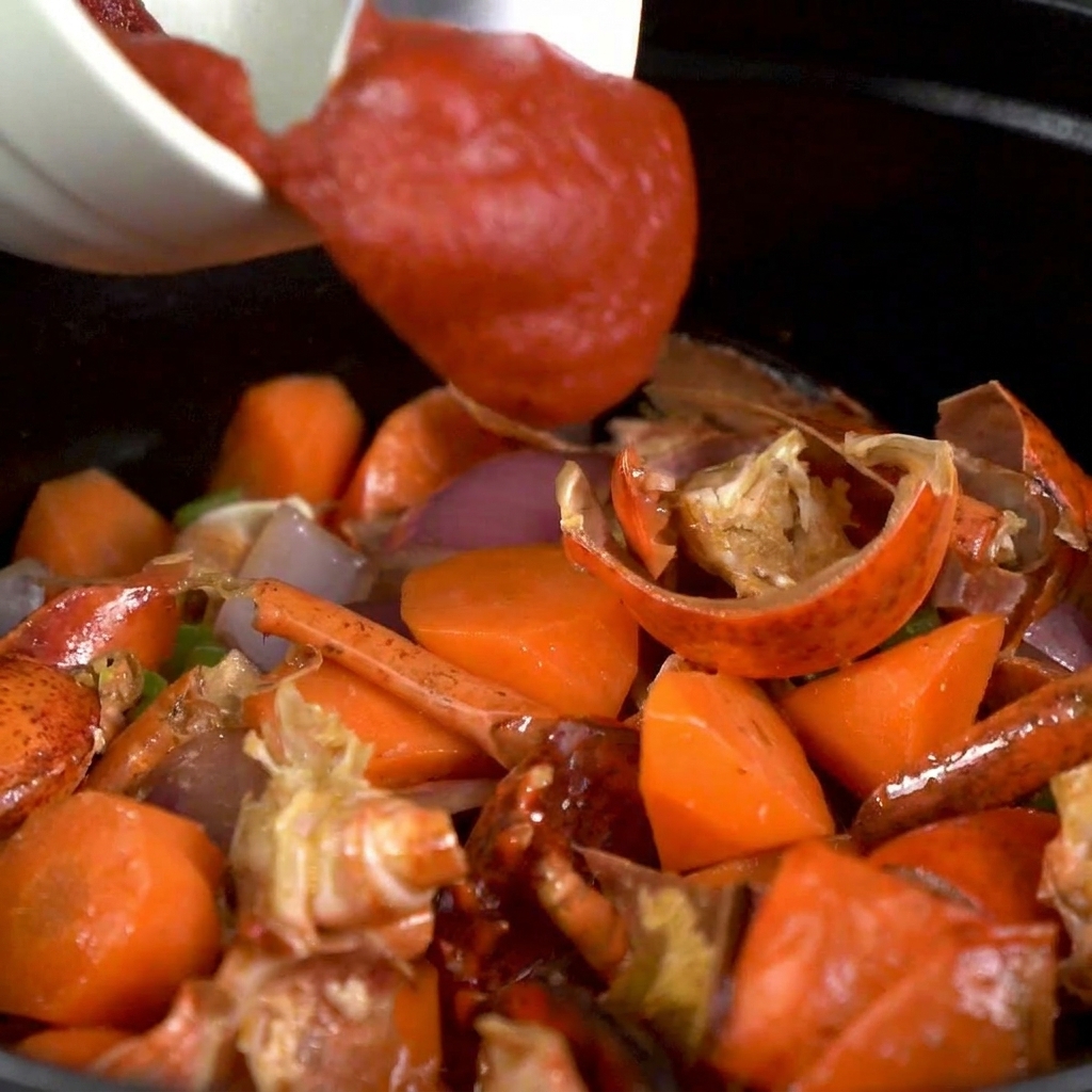 Concentré de tomate ajouté dans la marmite avec les légumes et les carapaces.
