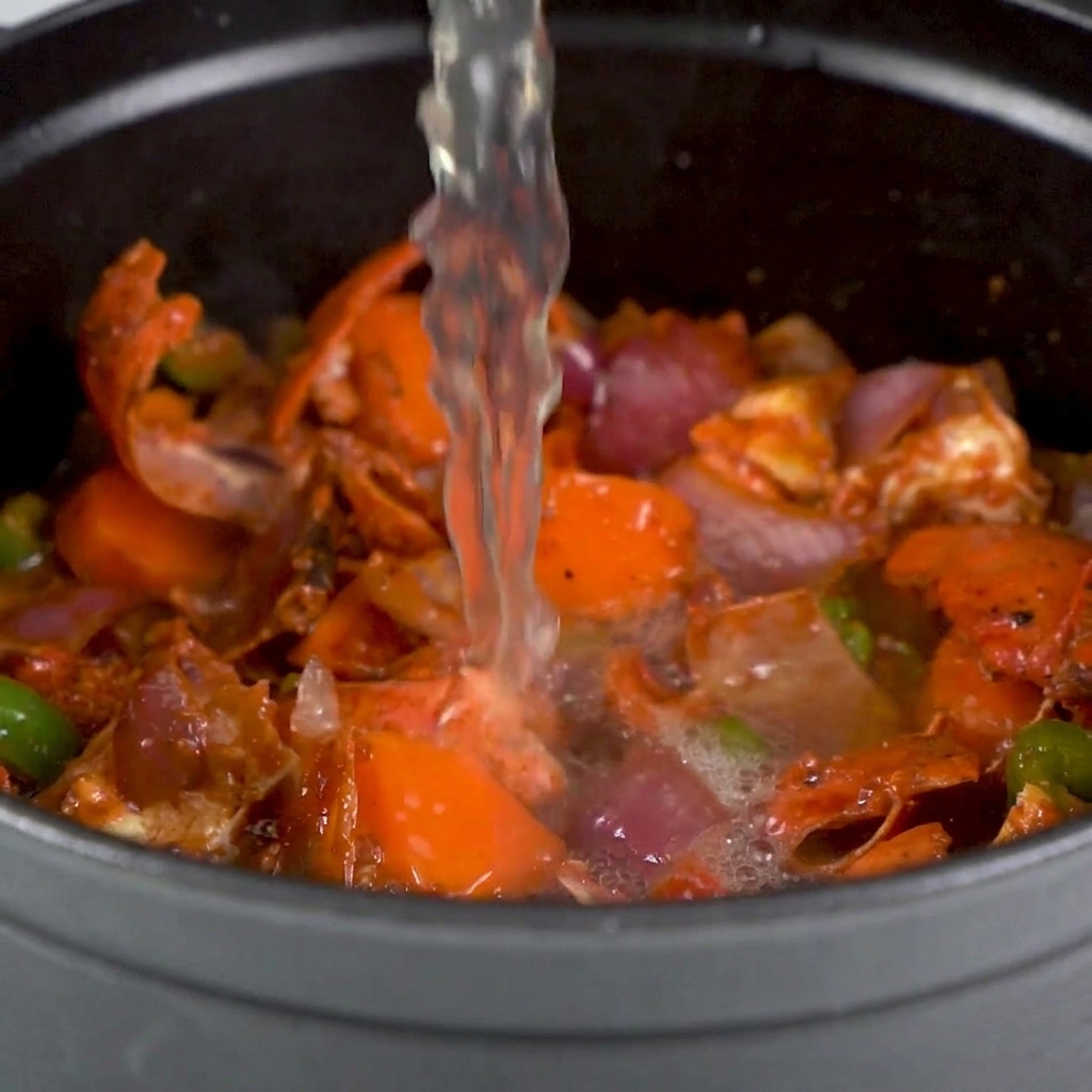 Le fond de fruits de mer versé sur les carapaces et légumes dans une grande marmite.