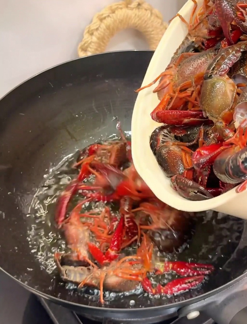 Ajout des écrevisses dans un wok très chaud rempli dhuile pour la friture.