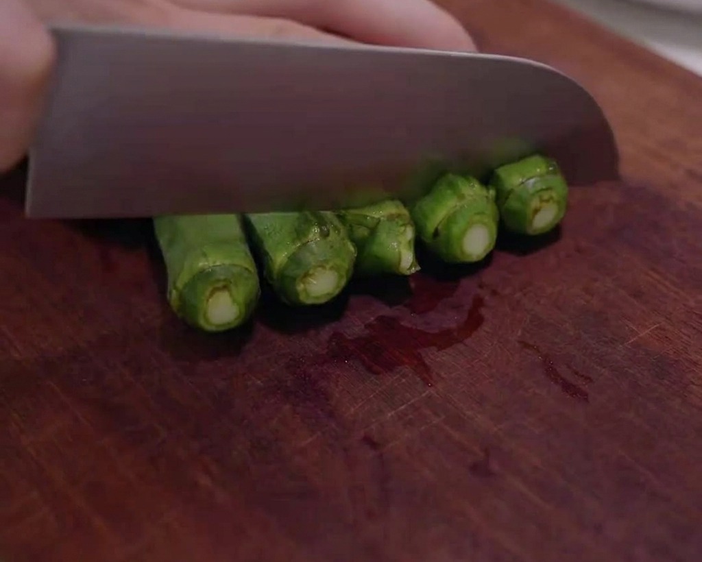 Gombos frais coupés en petites rondelles sur une planche à découper en bois.