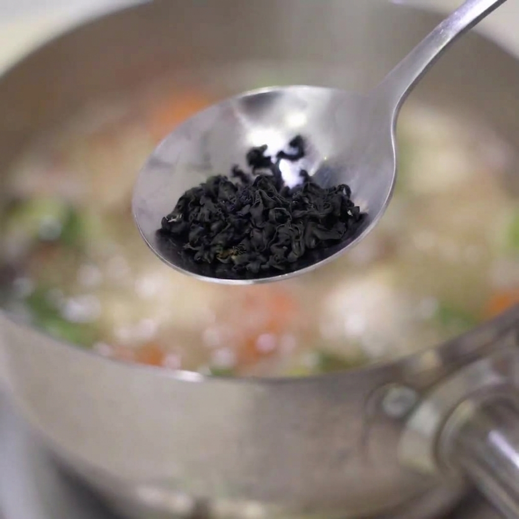 Algues wakamé séchées ajoutées dans la soupe frémissante.