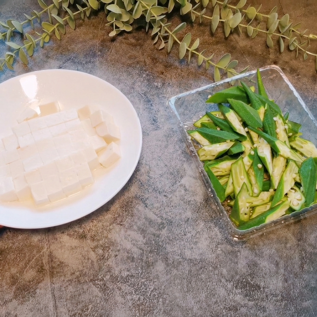 Un bloc de tofu soyeux coupé en petits cubes réguliers sur une assiette blanche.
