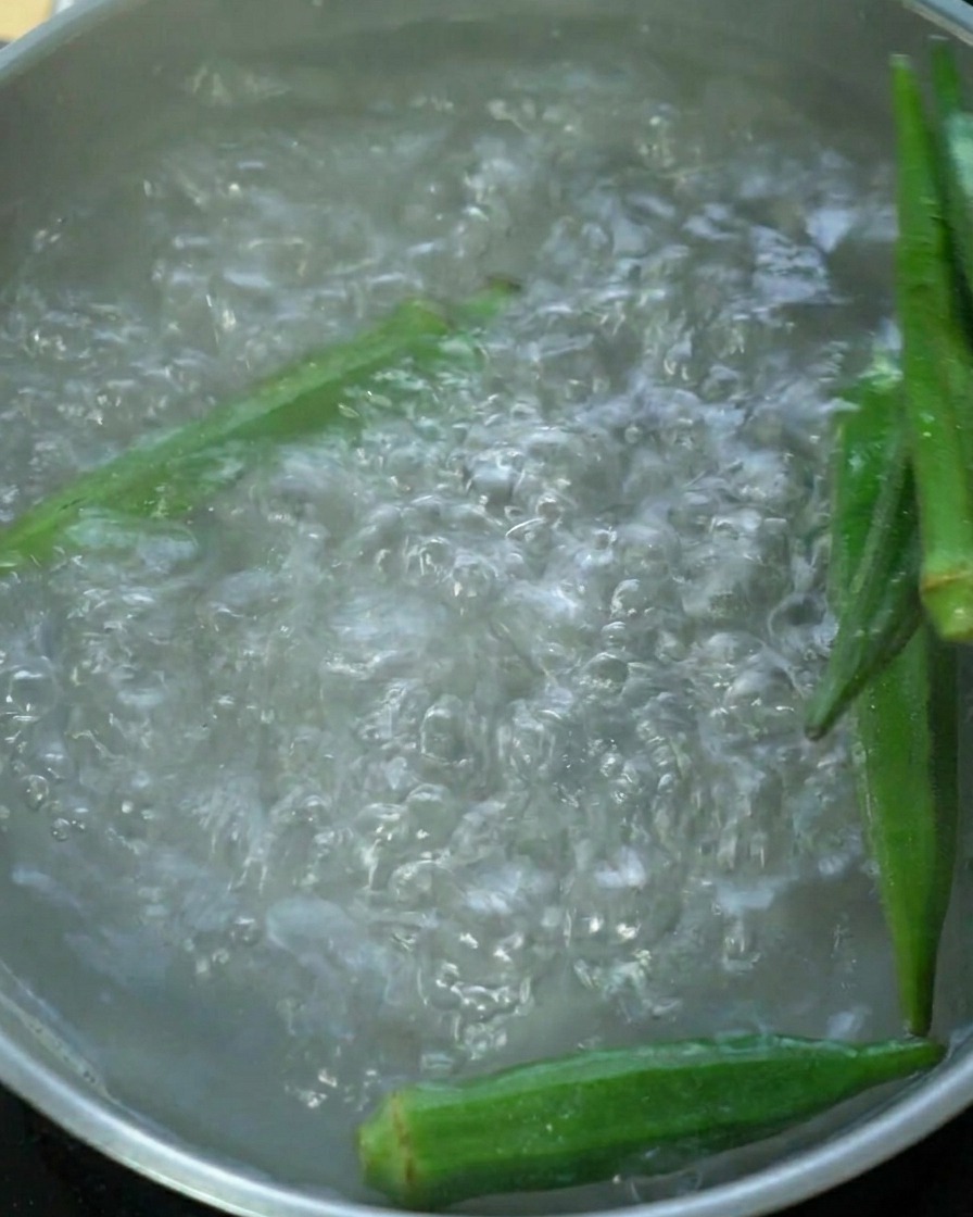 Gousses de gombo vert frais bouillies dans une casserole deau.