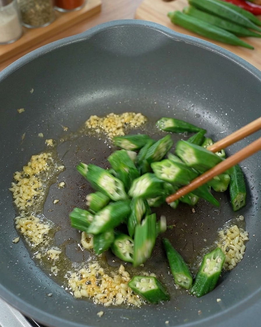 Rondelles de gombo sautées dans une poêle avec du gingembre et de lhuile.