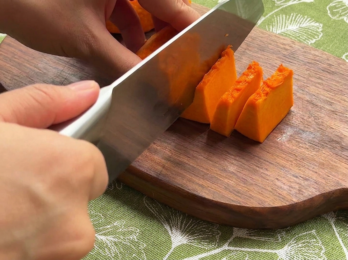 Potiron, oignon et carottes frais coupés en petits morceaux réguliers sur une planche en bois.