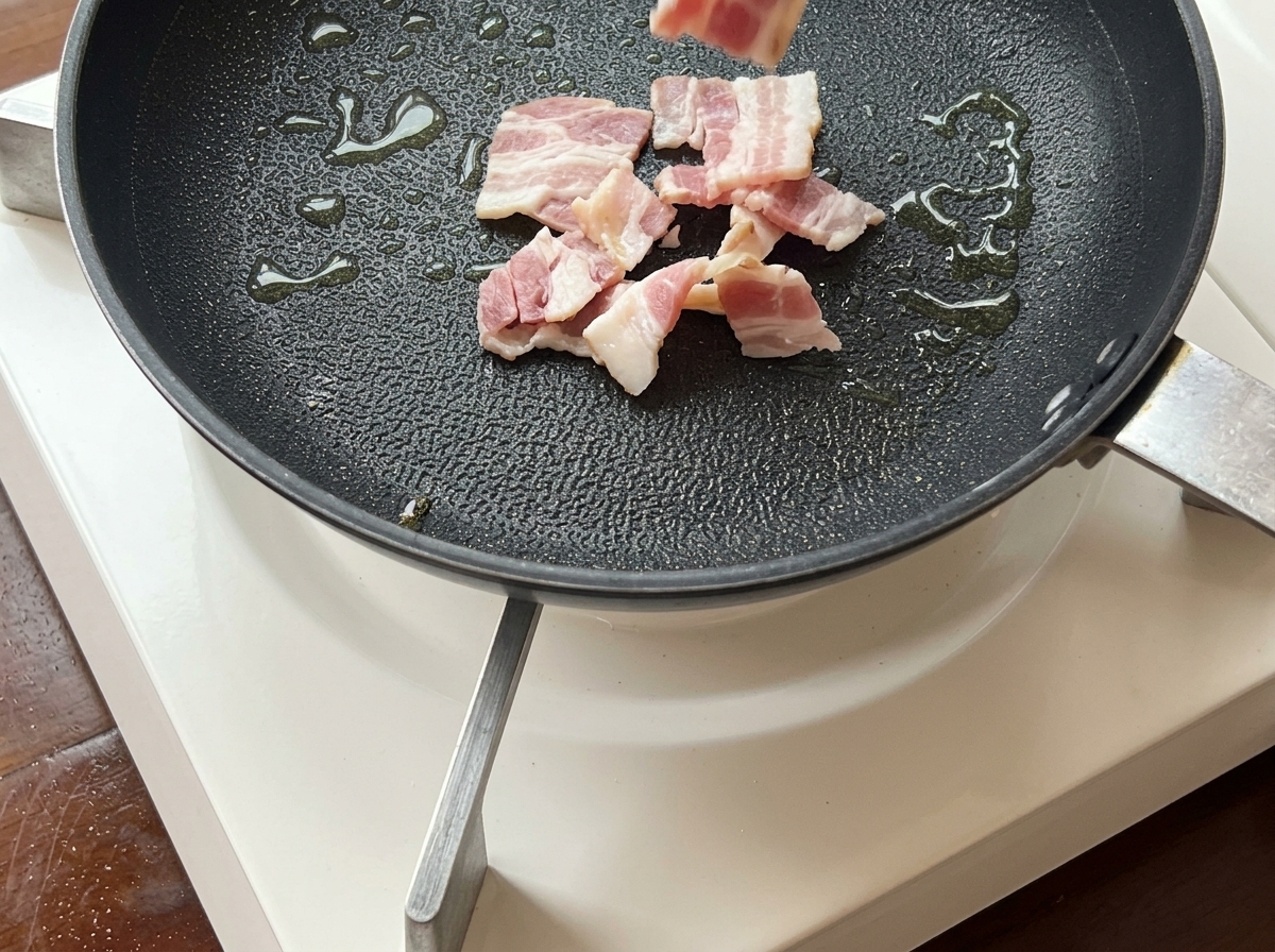 Tranches de bacon grésillant dans une poêle jusquà devenir dorées et croustillantes.