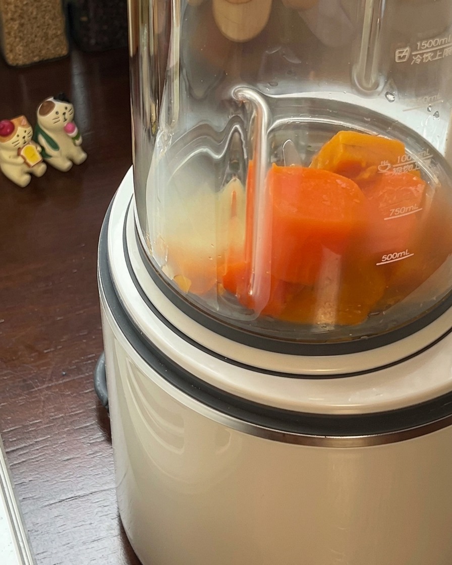Mélange de potiron et de carottes cuits versé dans un mixeur haute vitesse.