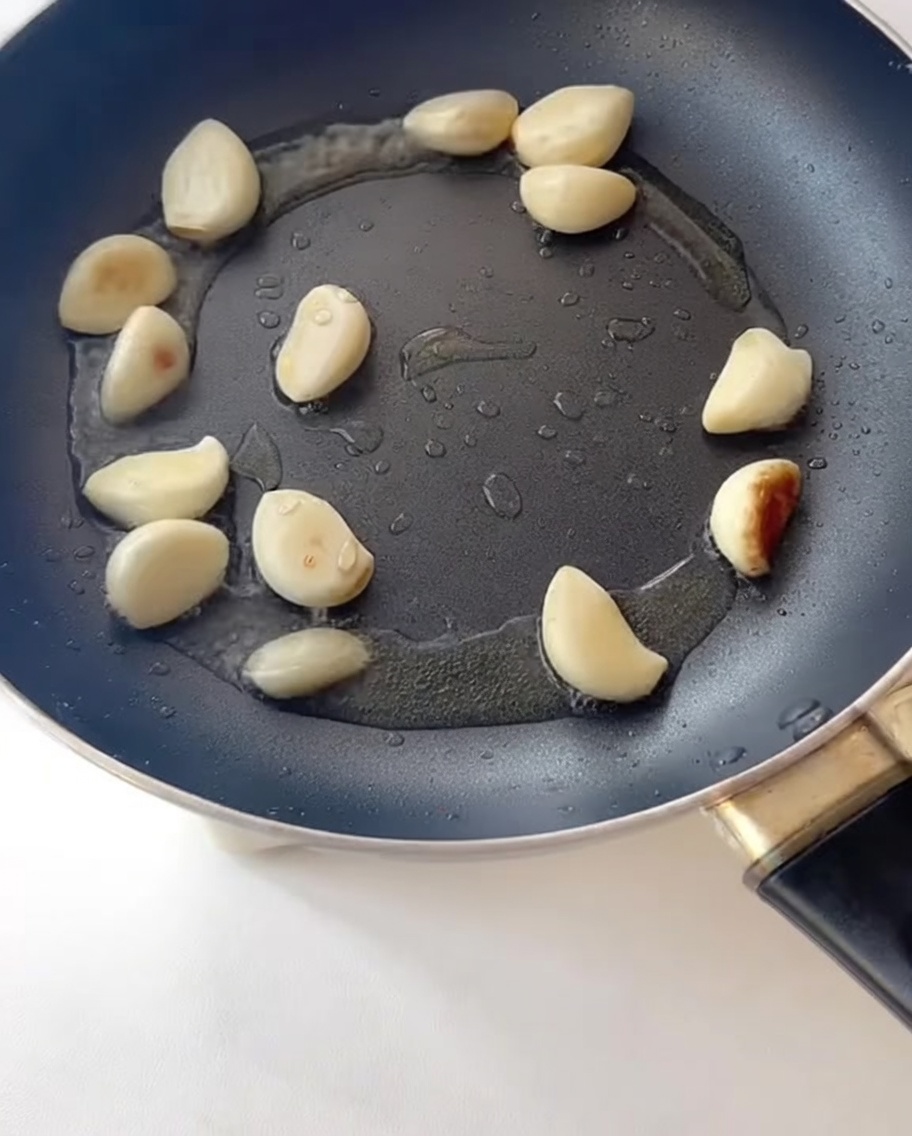 Tranches de bacon grillant dans une poêle à côté de lail.