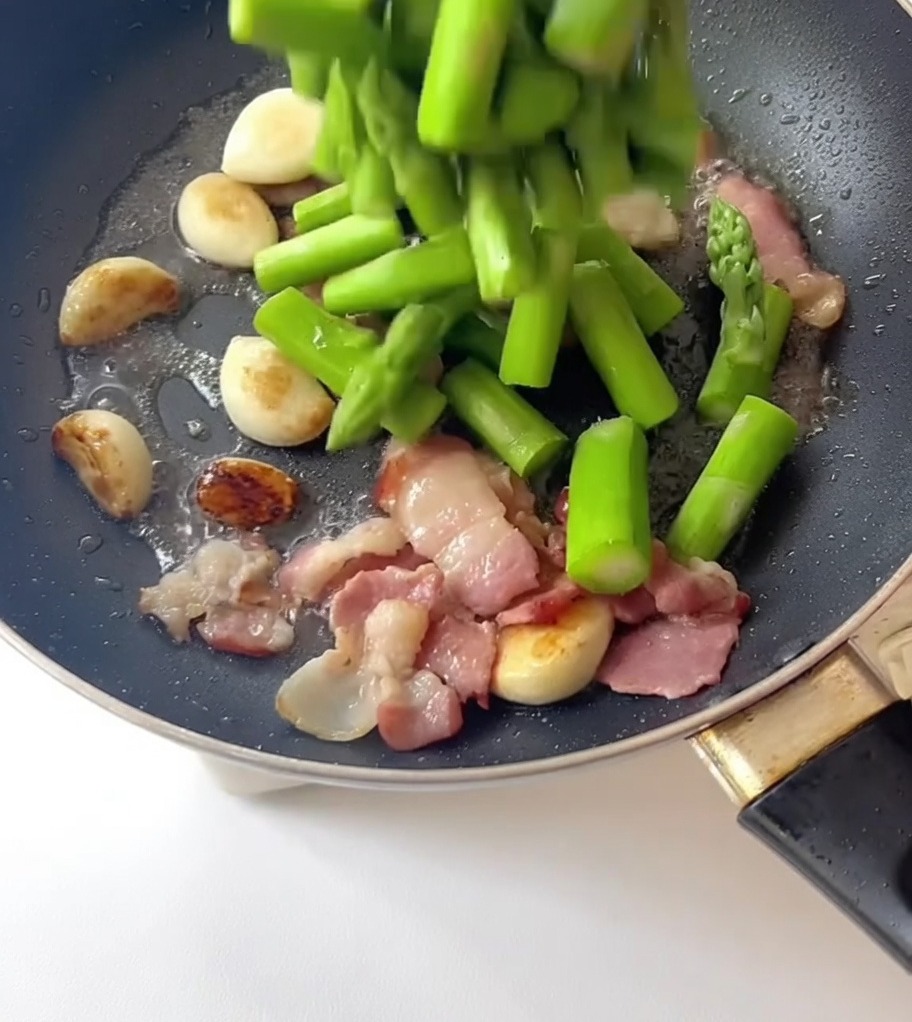 Asperges blanchies versées dans une poêle contenant lail et le bacon.