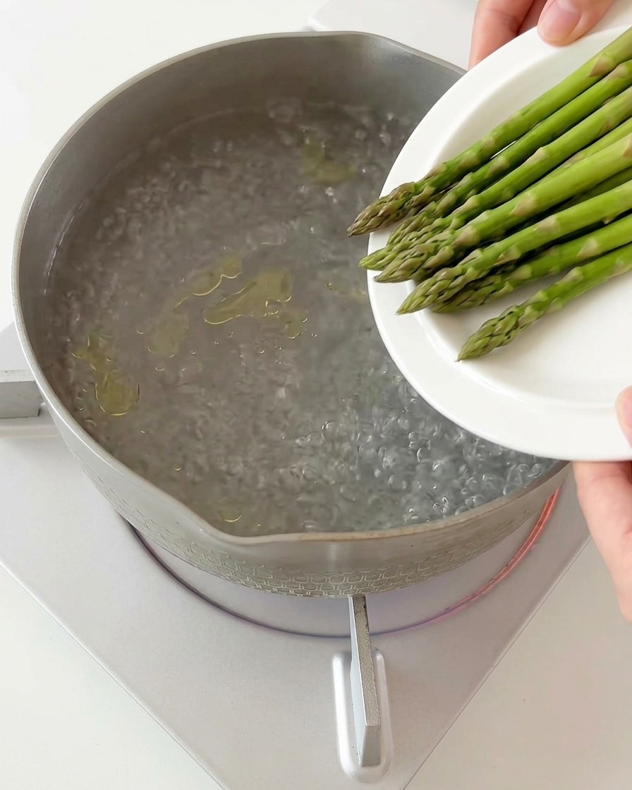 Morceaux dasperges plongés dans une casserole deau bouillante.