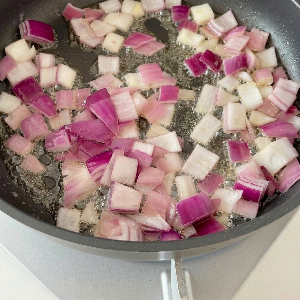 Morceaux de bacon en train de frire avec les oignons sautés.
