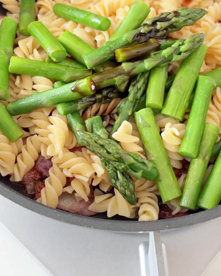 Sauce soja et sauce huître versées sur le mélange de pâtes, bacon et asperges.