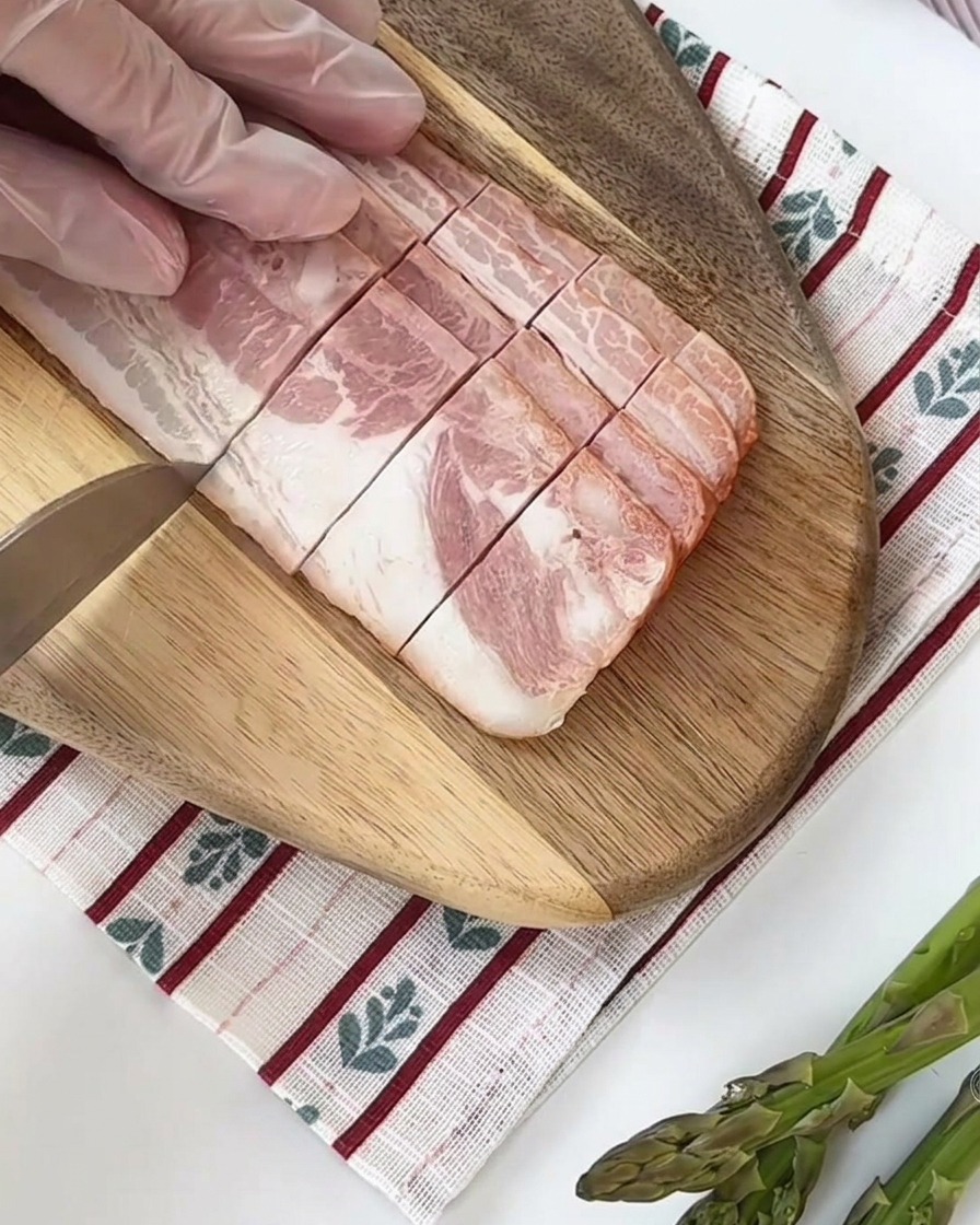 Tiges dasperges vertes fraîches coupées en segments égaux sur une planche à découper en bois.
