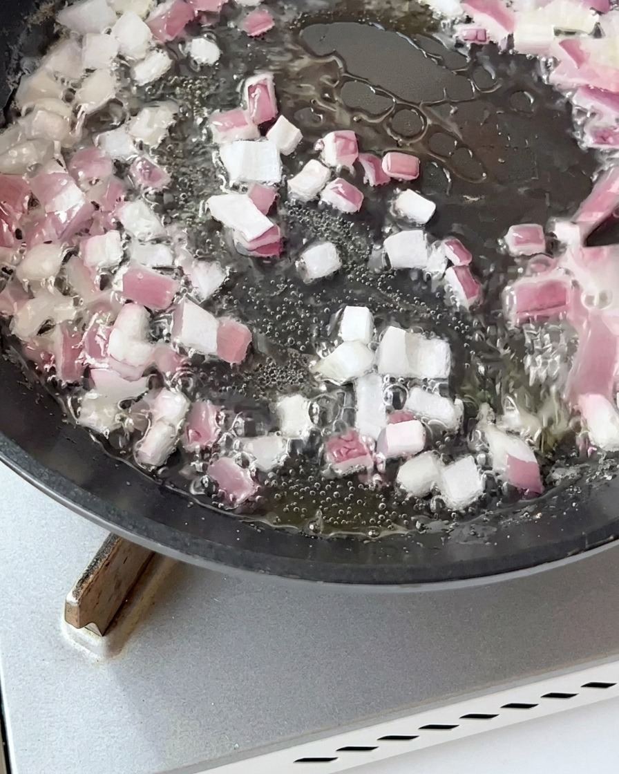 Morceaux de bacon sautant dans une poêle avec des oignons jusquà ce quils soient dorés.