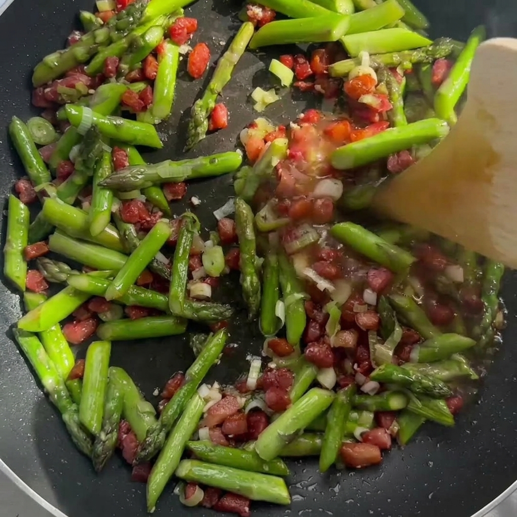 Crème versée sur le mélange bacon et asperges dans la poêle.