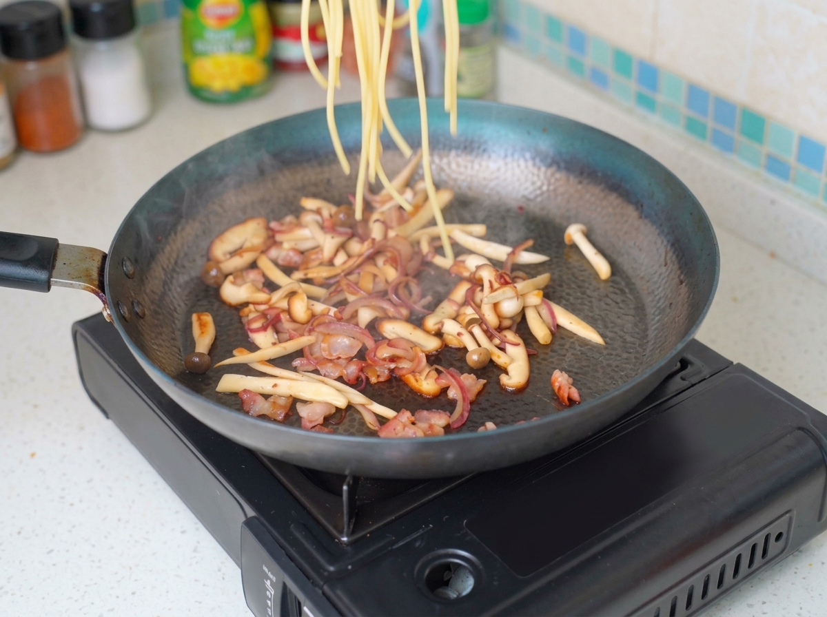 Cheveux dange cuits ajoutés dans la poêle avec le mélange bacon-champignons.