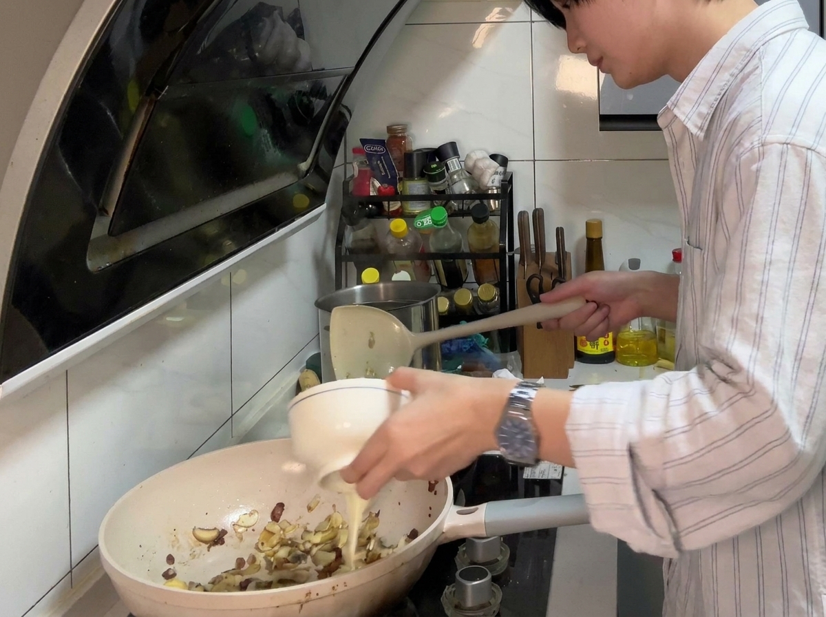 Une poêle contenant des champignons et des oignons sautés, avec des tranches de fromage fondu et du beurre formant une base crémeuse.