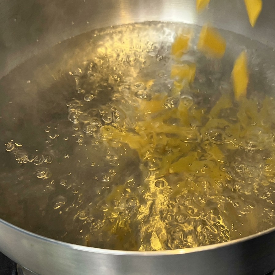 Des pâtes penne versées dans une casserole deau bouillante.