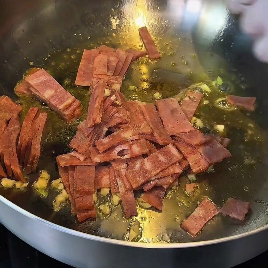 Bacon et ail rissolant dans une poêle, les bords du bacon prenant une belle couleur dorée.