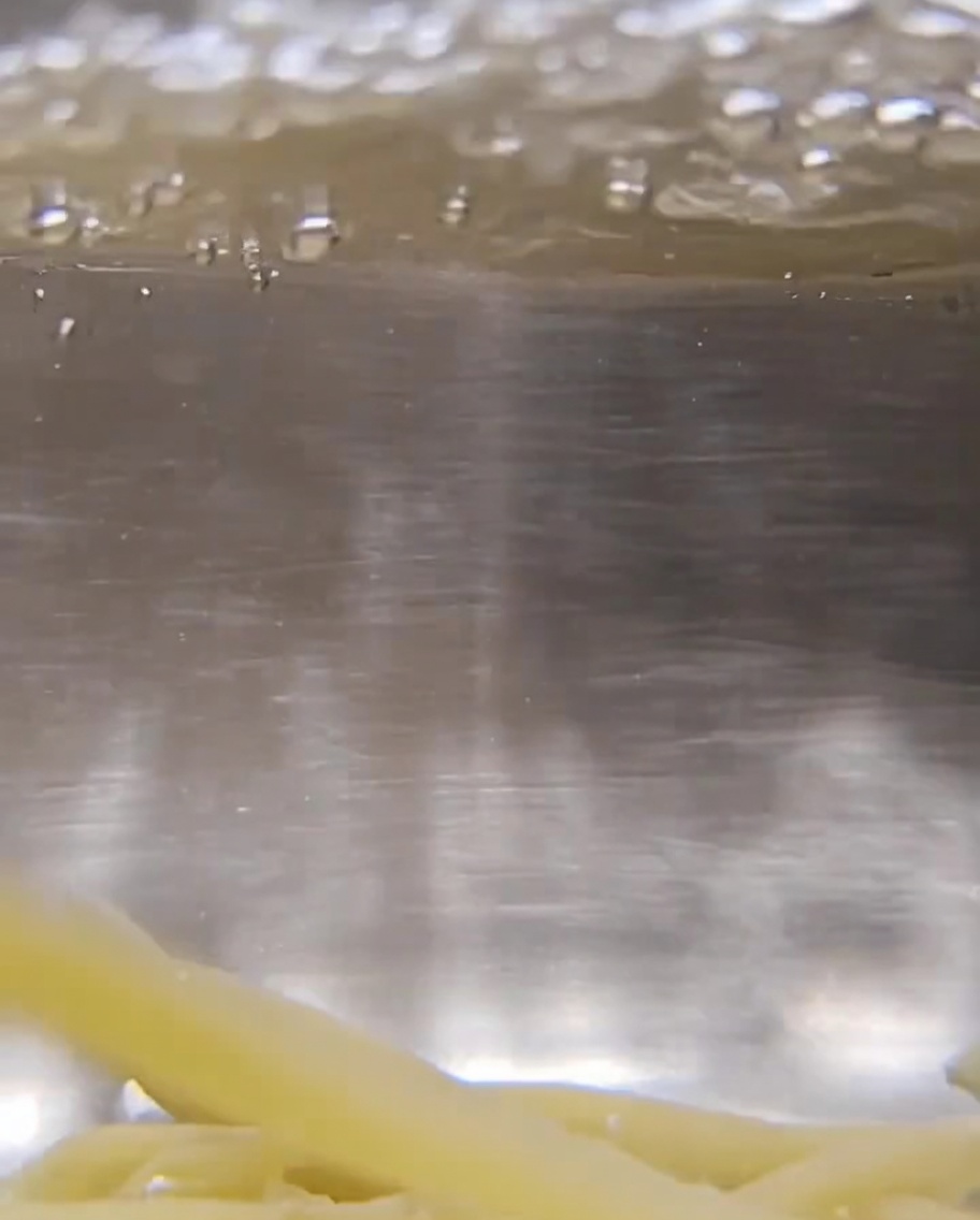 Gros plan sur des pâtes Trofie torsadées sèches immergées dans de leau bouillonnante.