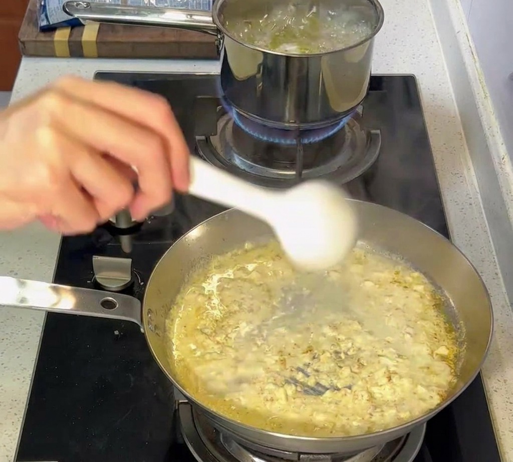 Pinces transférant les pâtes al dente de la casserole deau bouillante vers la poêle à sauce crémeuse.