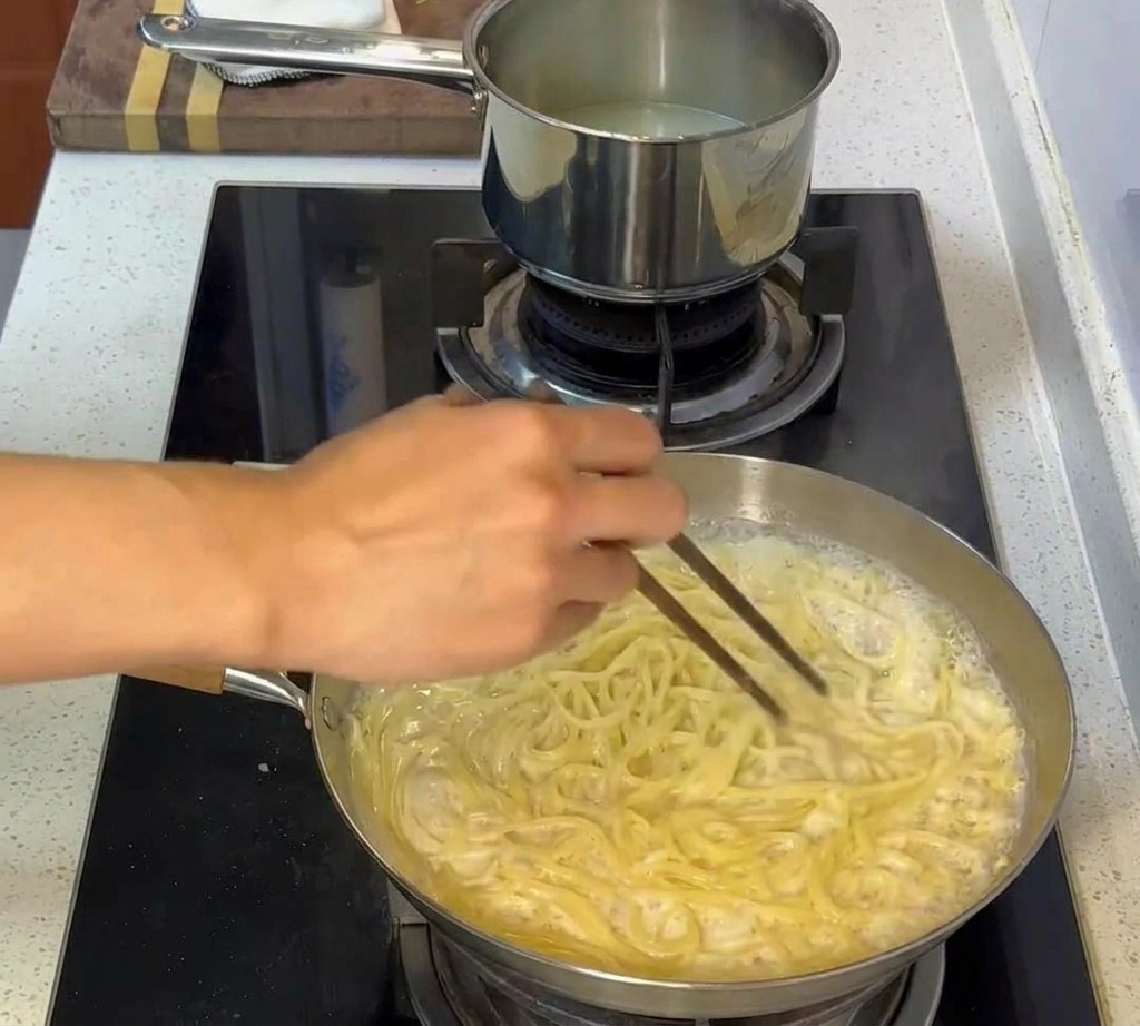 Pâtes mélangées à la sauce crémeuse, enrobant soigneusement chaque brin.