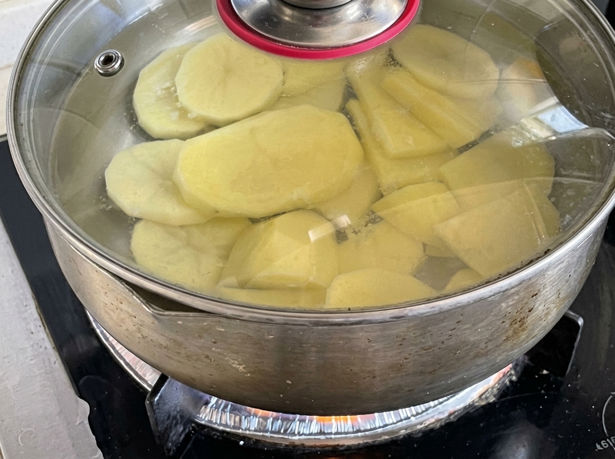 Des rondelles de pomme de terre frémissant dans une casserole deau couverte sur la cuisinière.