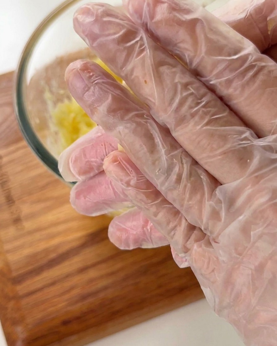 Mains portant des gants en plastique façonnant de la pâte de pomme de terre en un petit fond de tartelette en forme de bol.