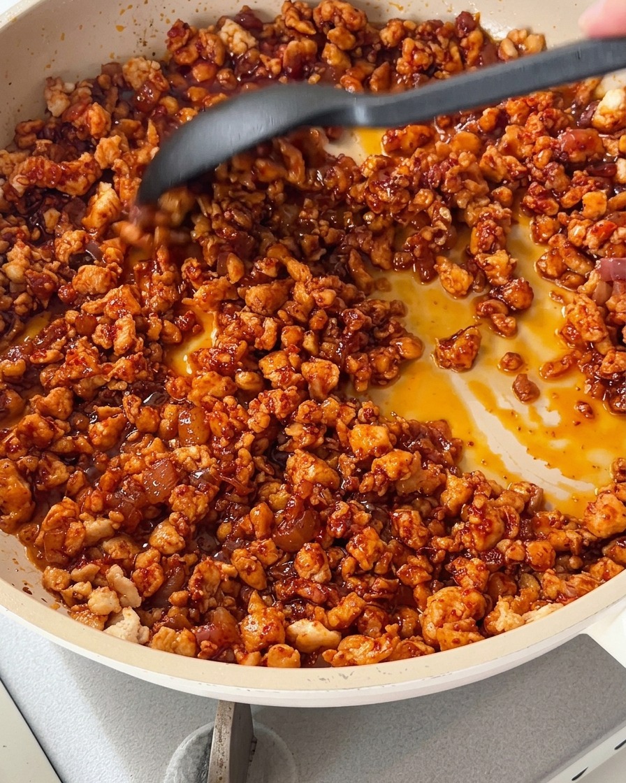 Cuisson du mélange de poulet avec des dés de poivrons colorés dans une poêle.