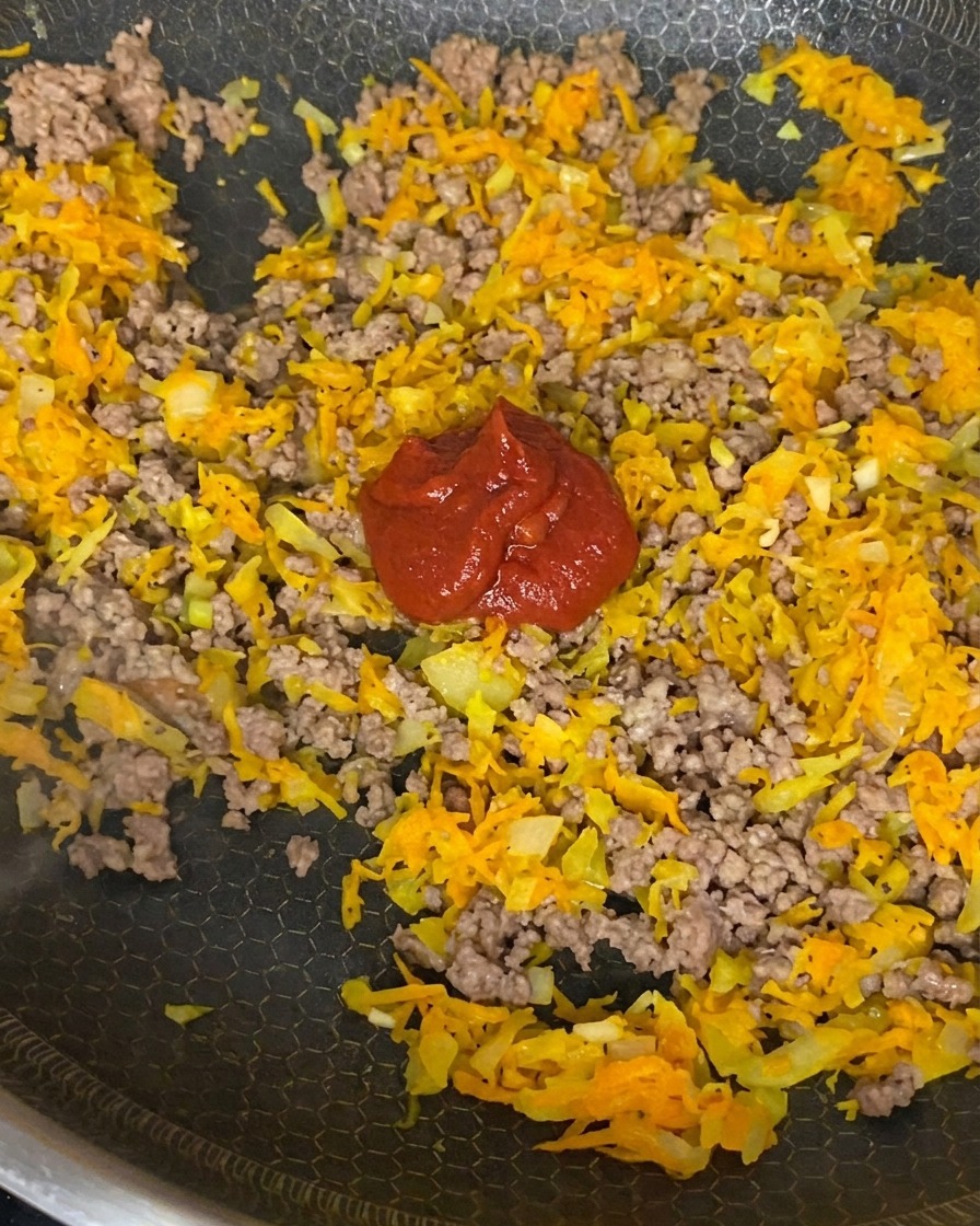 Concentré de tomate, purée de tomates et sauce soja ajoutés à la viande et aux légumes dans la poêle.