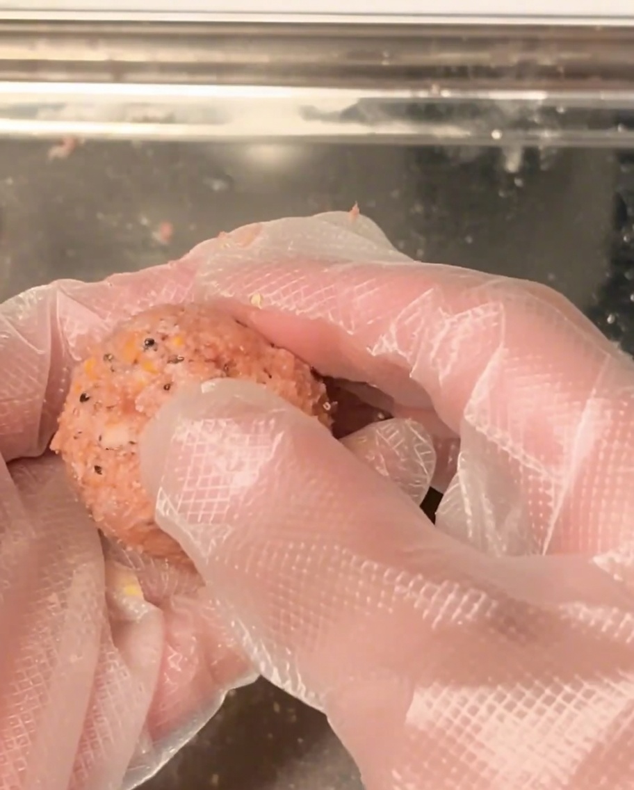 Mains roulant de la viande hachée crue en une boule ronde et uniforme.