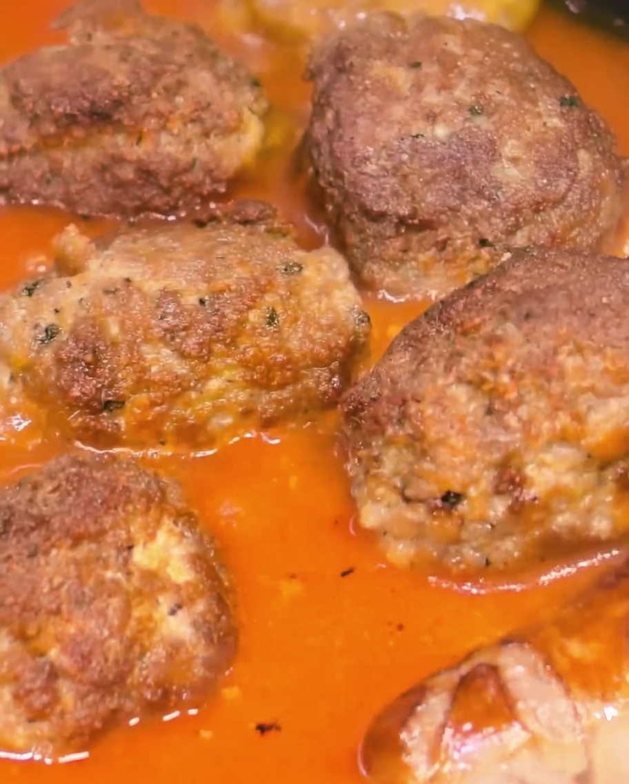 Grosses boulettes de viande et saucisses mijotant ensemble dans une sauce tomate riche et épaisse.