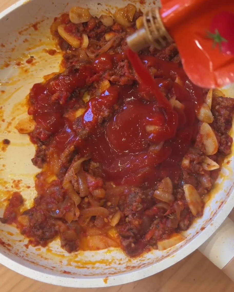 De la sauce piquante mexicaine versée directement dans la poêle où mijotent la viande et les tomates.
