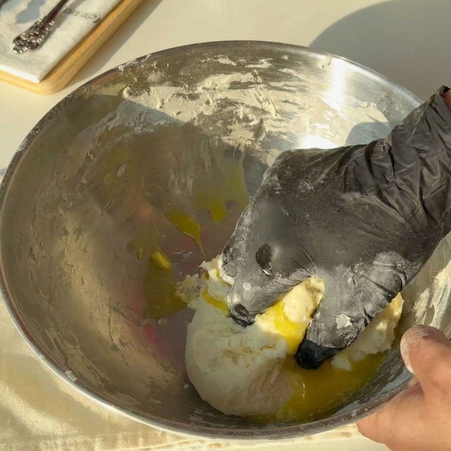 Beurre fondu doré versé sur une masse de pâte dans un bol en métal.