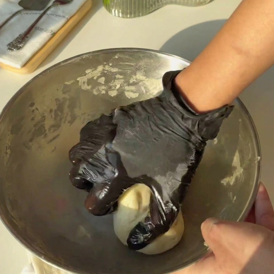 Pâte lisse pétrie à la main dans un bol mélangeur en métal.