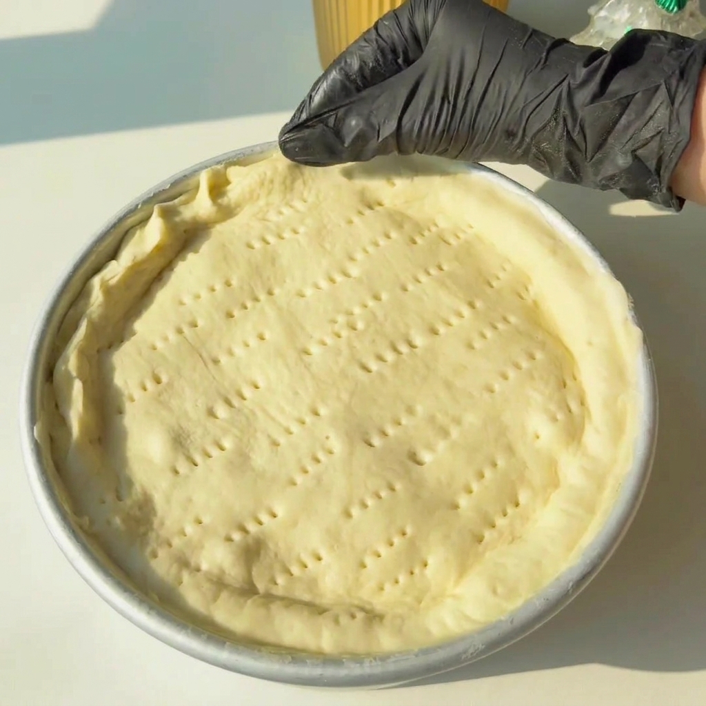 Mains pinçant les bords de la pâte pour sceller les couches supérieure et inférieure ensemble.