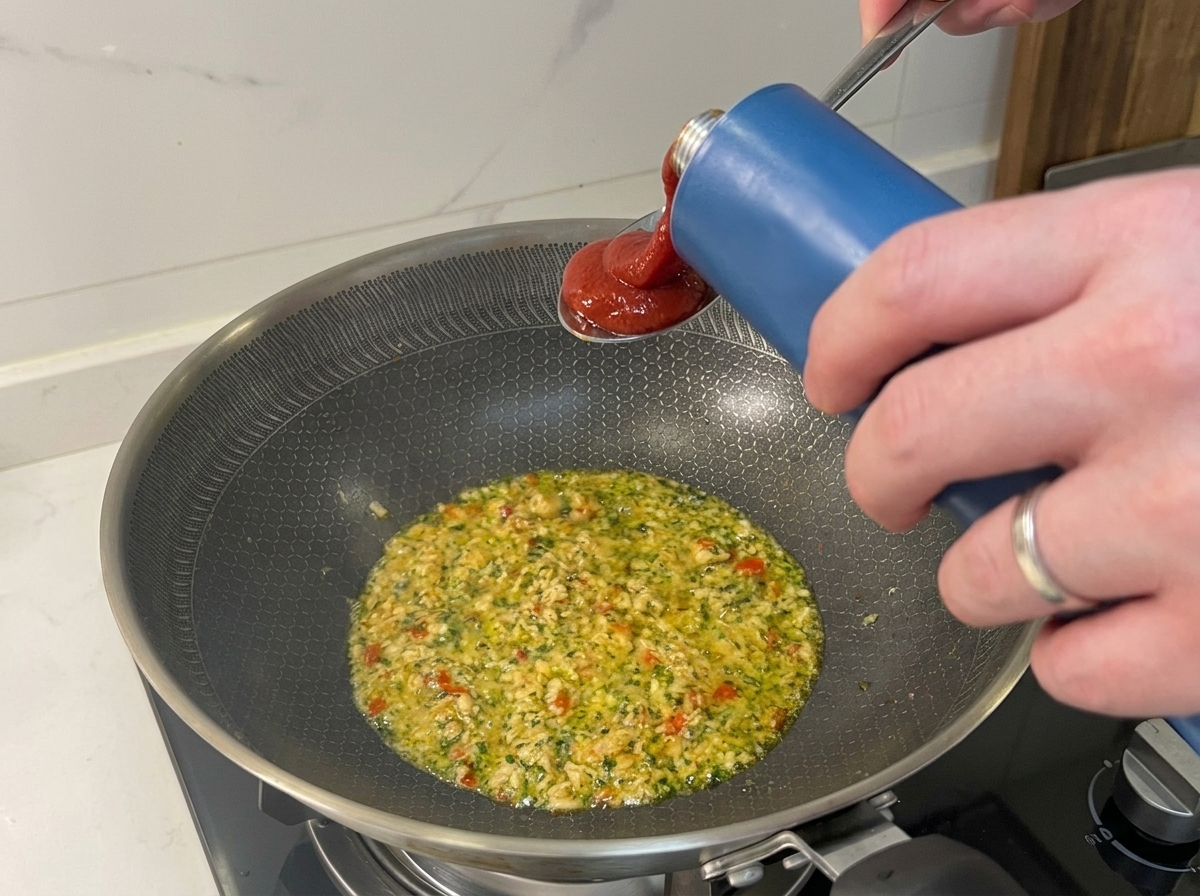 Verser du coulis de tomate dans une poêle contenant le thon sauté et les aromates.