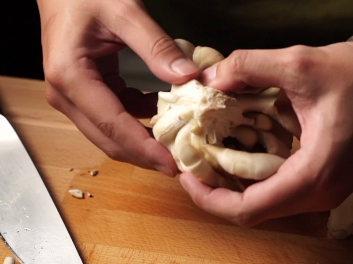 Des mains déchirant des champignons frais en petits morceaux.