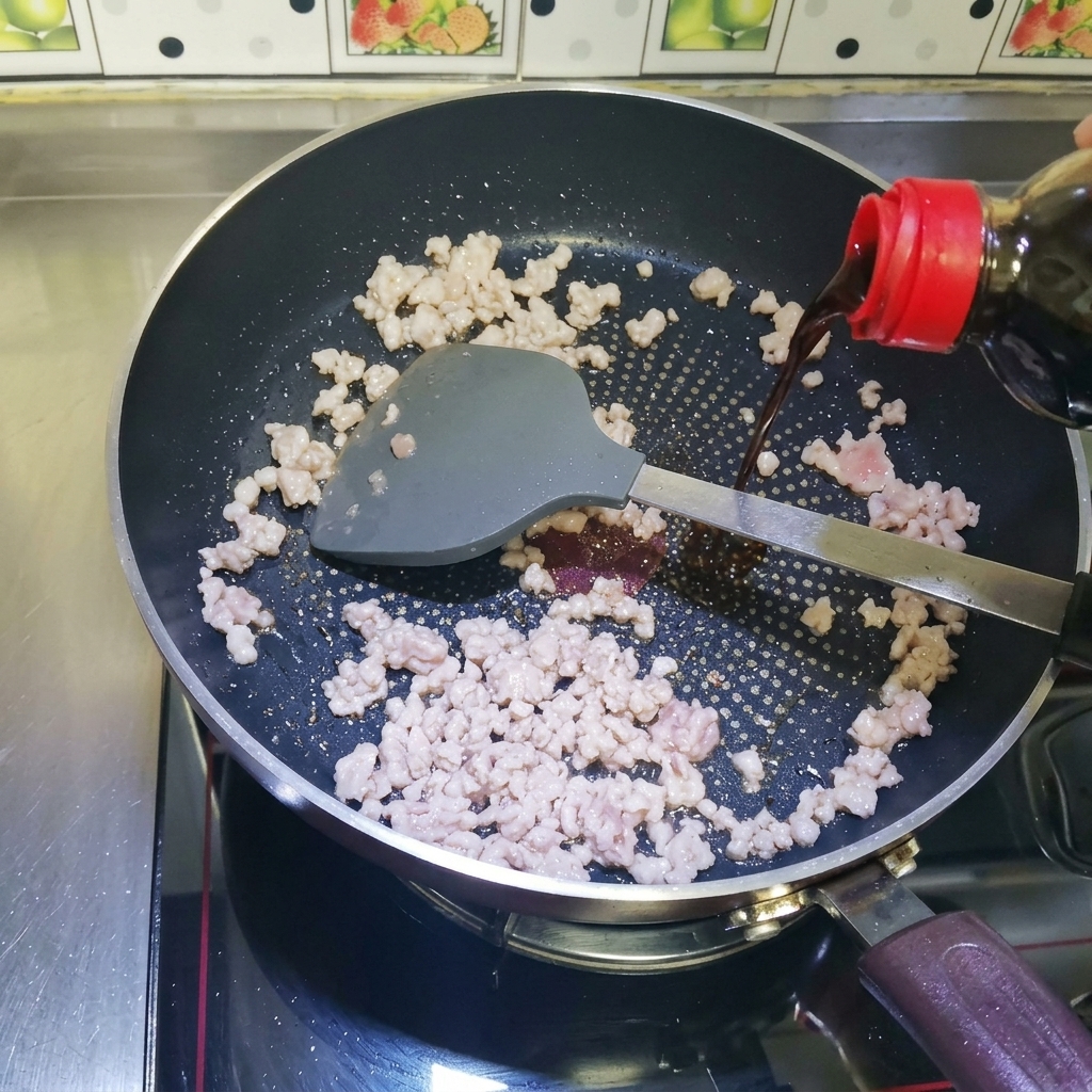 Sauce soja versée sur la viande hachée dans la poêle.