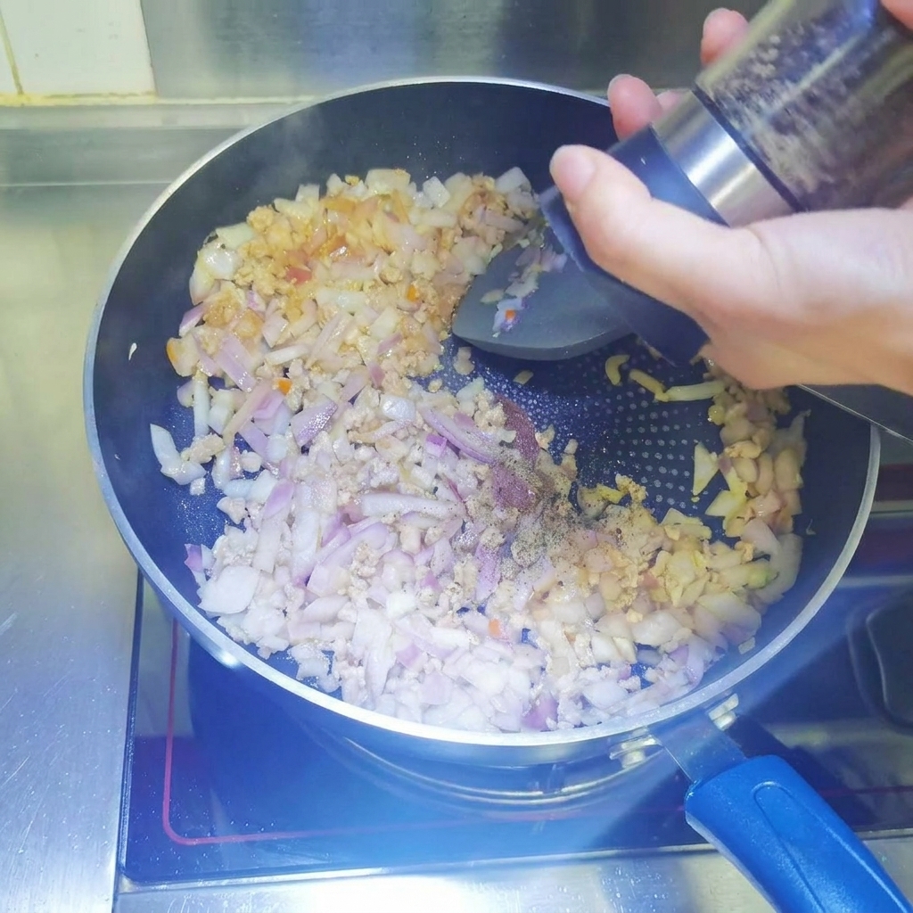 Poivre noir fraîchement moulu ajouté dans la poêle.