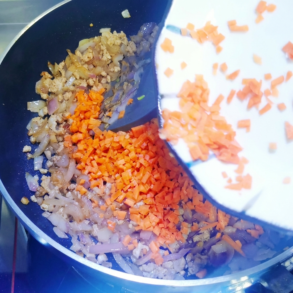 Dés de carottes ajoutés dans la poêle et mélangés.